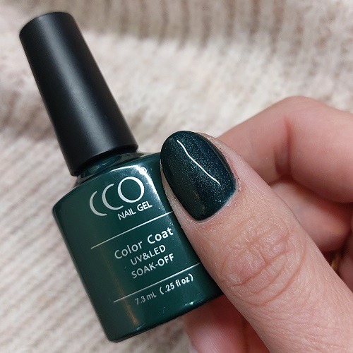 Vinger met donker groen gelakte nagels en een gellak flesje van het merk CCO