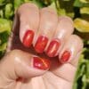 Hand met rode nagels gelakt met een Cat's eye kleur 'Bazahr' van Gelzz