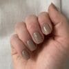 Hand met donker nude gelakte nagels in de kleur 'New Nude Light Taupe' van het merk Gelzz