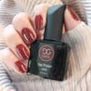 Donker rood gelakte nagels in de kleur 'Red Brick' van Gelzz met een flesje Gelzz