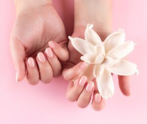 Hand met roze gelakte nagels en een bloem