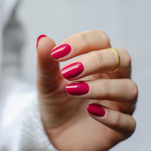 Hand met rood gelakte nagels in de kleur 'Business Sophisticated' van het merk Gelzz